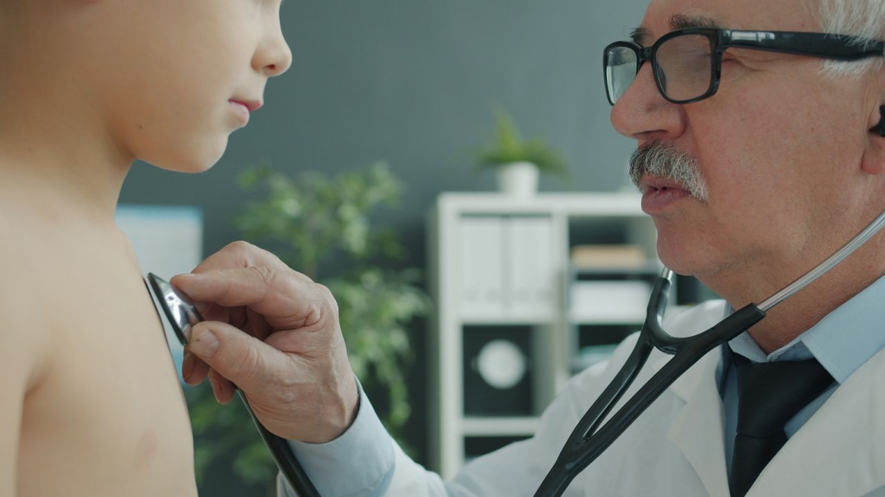 Offerings Senior doctor examines young patient with stethoscope in modern clinic.